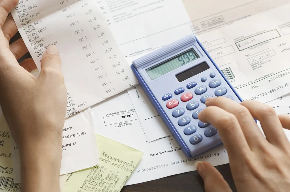 Persona revisando talón de nómina y usando calculadora para sacar su capacidad de pago de préstamo